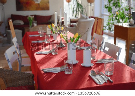 improvised dining table for many guests with red tablecloth and decoration in the living room, selected focus, narrow depth of field