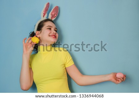 Teen girl covered her eyes with eggs and stuck out her tongue. Teen girl with bunny ears Easter, Copy space