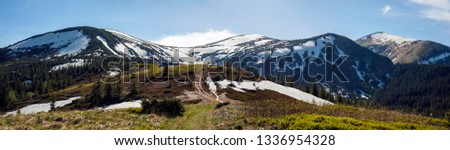 Panoramic photo of mountain range in sunny day in the spring season. Beautiful view of mountains covered in snow in spring.