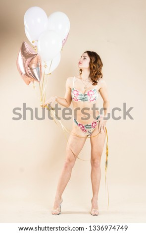 Girl with helium balloons in different clothes, on a beige background. Pastel colors photo. Emotions and poses. Close up.