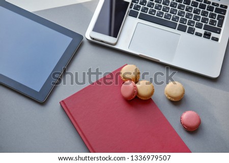 Top view. Open laptop, tablet, smartphone, notebook and colorful French macaron on a table. Work, lunch, office