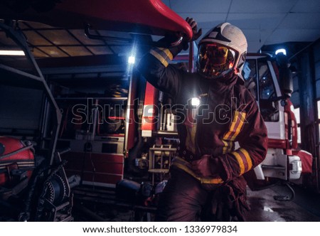 Fireman wearing a protective uniform with flashlight included working in a fire station garage