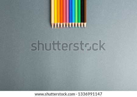 colored pencils in row on a gray background top view. Art set of pencils for schoolboy with free space. view from above