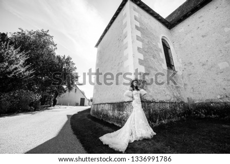 Black and white photo of a gorgeous bride in a beautiful wedding dress who poses near the old building in her happy wedding day