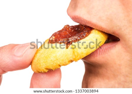 Detailed closeup shoot of the mouth part of a young pretty and funny man who eats ginger biscuit isolated on abstract blurred white background