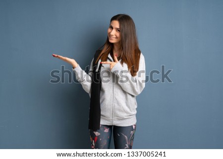 Young sport woman holding copyspace imaginary on the palm to insert an ad