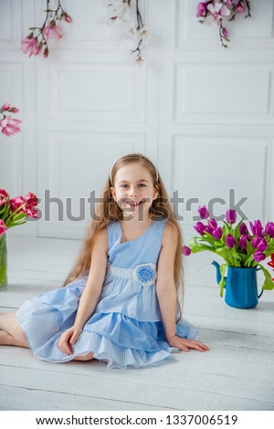 Portrait of a beautiful blue-eyed girl, a little girl among spring flowers in a bright room. Spring break, Mother's Day, Women's Day, Easter.