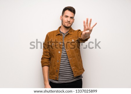 Handsome man over white wall happy and counting four with fingers
