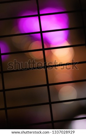Pink Lights shining through a wire grate with a bokeh effect