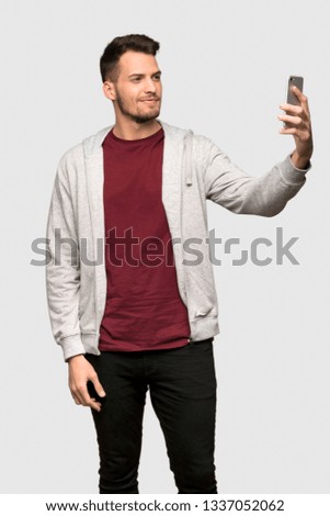 Man with sweatshirt making a selfie over grey background