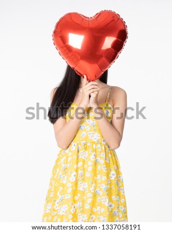 Asian young woman in yellow dress hold  red balloon heart. Young woman holding it with  being excited and surprised  holiday present isolated white  background.concept love surprise valentine day.