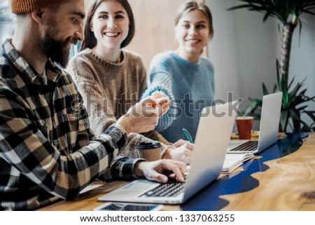 Young cheerful people smile and gesture while working in cafe. Team job. Photo young and mature businessmans working with new startup project. Teamwork, business, creative meeting, cooperation concept
