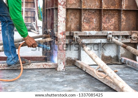 Welder worker welding steel structure outdoor at building construction site without protection.