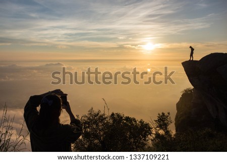 Silhouette man taking photo on top of a Mountain.