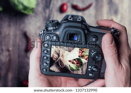 Man taking photo of Traditional mexican tortilla wrap with vegetables and grilled chicken meat on wood table