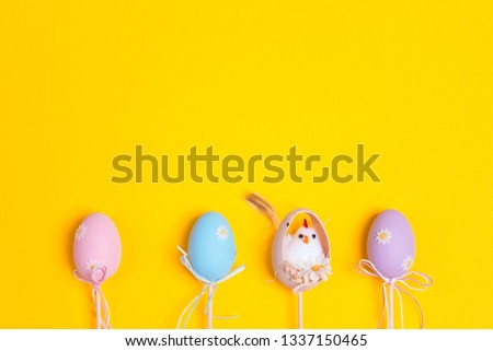Easter border of decorative eggs on yellow background. Top view, space for text.