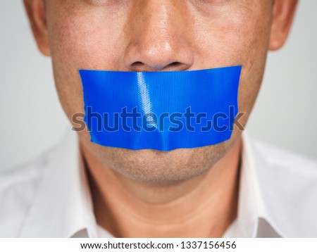 Man is silenced with adhesive red tape across his mouth sealed to prevent him from speaking. Freedom Concept. Royalty-Free Stock Photo #1337156456