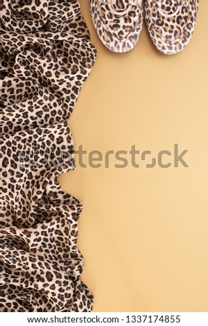 Animal print textile scarf and suede shoes on yellow background. Top view point.