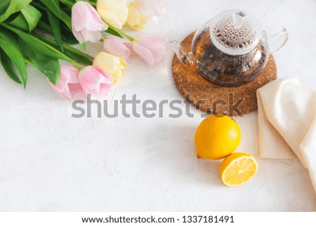 teapot with black tea, lemon and flowers on white table. Copy space. Spring tea party. Top view.