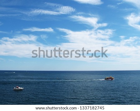 Beautiful seascape with red boat tour and white speedboat sailing in blue sea and blue sky with white clouds. Summer, South of France.                                