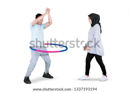 Picture of a young man and his wife exercising with a hula hoop in the studio, isolated on white background