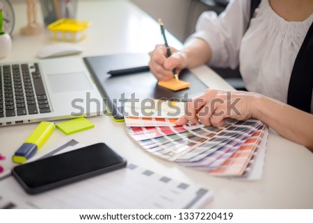 graphic designer working with computer and color swatch. creative woman using digital tablet at modern office. Architect using work tools and sample colour catalog