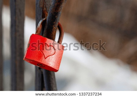 Red love padlock attached to steel fence. Rusty lock with heart shape carved hanging on railing outdoors. Valentines day, unity, memory concepts