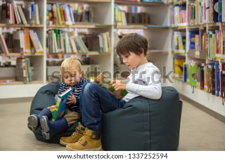 Smart children, boy brothers, toddler and school kid, educating themselves in a library, reading books and looking at pictures