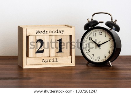 Wood calendar with date and old clock. Wednesday 21 April