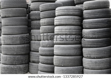 Old used tires stacked with high piles in secondary car parts shop garage