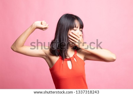 Sleepy young Asian woman yawn on pink background