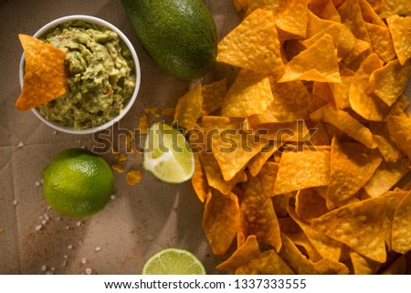 Golden tortilla chips with guacamole on a craft paper background. Mexican food.