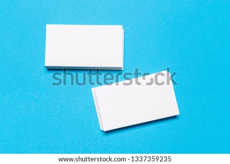 Blank white business cards on blue background. Mockup for branding identity. Template for graphic designers portfolios. Top view.