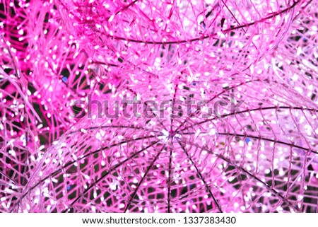 Pink and white decorative lights on a round steel frame designed like a rattan ball.