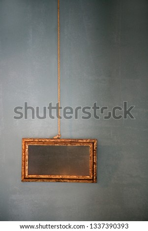 empty picture in a frame hangs on a rope on the wall
