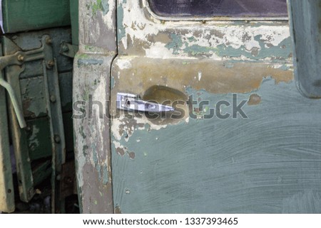 Green door of an old military vehicle with a chrome handle close up