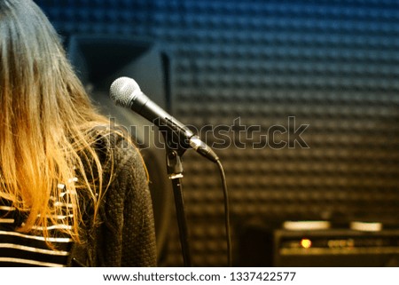 Microphone close - up on the background of a professional recording Studio. Workplace singers and musicians. Microphone stand and girl for recording vocals, speakers and sound of musical instruments.