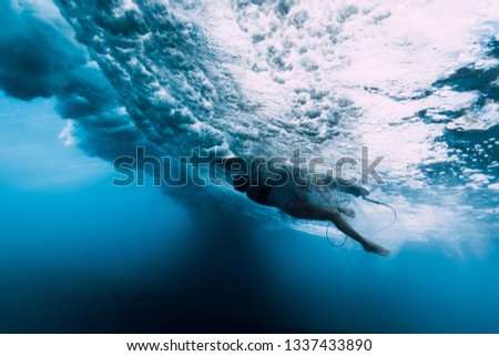 Surfer dive underwater. Surfgirl dive under big wave