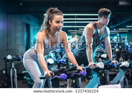 Attractive woman and handsome man doing spinning on cycling bikes Royalty-Free Stock Photo #1337436224