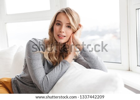 Image of cute pretty woman sitting indoors at home looking camera.