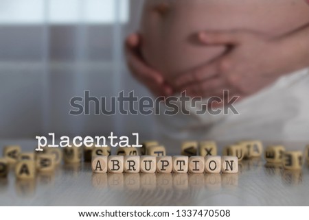Words PLACENTAL ABRUPTION composed of wooden letters. Pregnant woman in the background Royalty-Free Stock Photo #1337470508