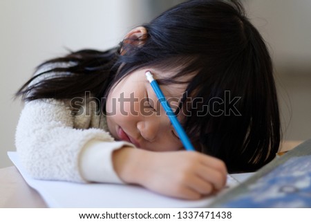 Asian young child girl fall asleep while studying on table with books