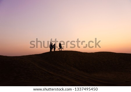 silhouette of five friends in beautiful evening in desert
