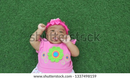 Cute babies wear pink dresses and bandana with pink floral motifs with natural green backgrounds.
