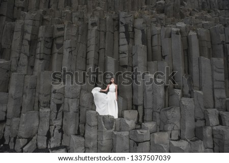 The girl in a wedding dress is on the rocks in Iceland