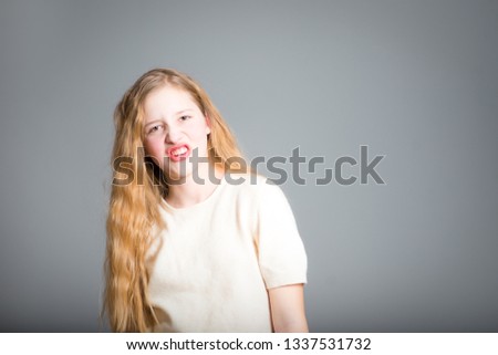 little girl grimaces, studio photo over background