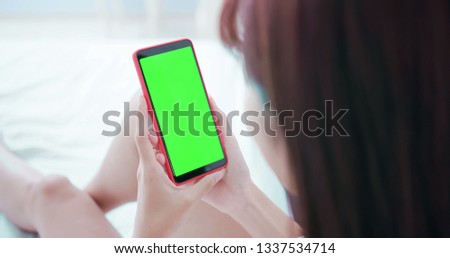 woman take cell phone with green screen in the bed at home