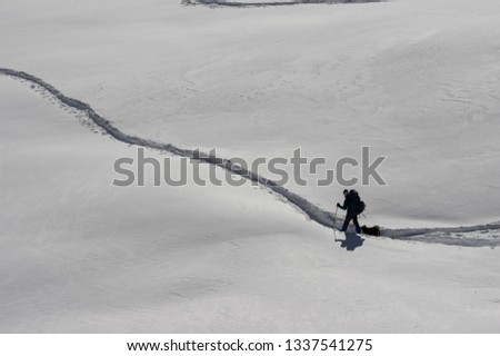 A person trekking down a deep path in the snow covered landscape.