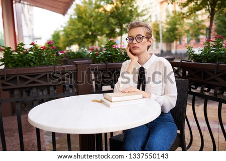 Pretty woman sitting in a street cafe at a table with a book