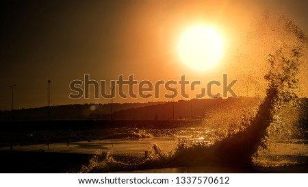 high wave in front of the sun Royalty-Free Stock Photo #1337570612